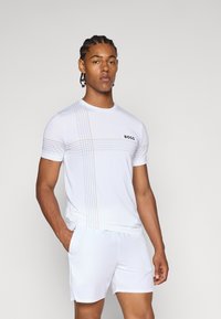 T-shirt sportivo bianco a maniche corte, con linee orizzontali arancioni e grigie e logo "BOSS" sul petto. Tessuto leggero.