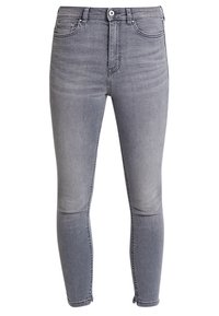 Jeans ajustados grises de denim, con talle alto, bolsillos frontales y detalles de cremallera en los tobillos. Textura suave con desvanecidos.