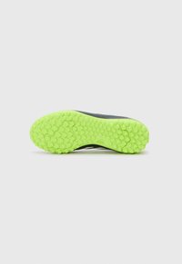 Zwarte sportieve schoenzool met een felgroen hexagonaal-patroon profiel en een gestructureerd oppervlak voor grip. Bevat een logo op de hiel.