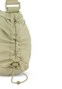 Torebkę z jasnego khaki materiału charakteryzuje marszczona tekstura, regulowany pasek oraz zapięcie na suwak, zapewniające bezpieczeństwo. Kompaktowy i minimalistyczny design.