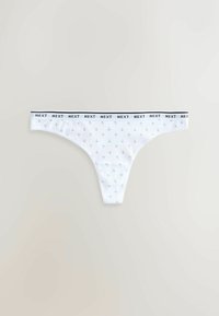 String-tanga blanc pour femmes avec un petit motif floral et une ceinture ornée du texte répété "NEXT" en noir.