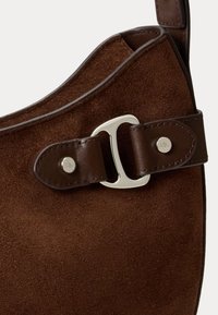 Borsa in suede marrone con tracolla in pelle liscia, fibbia metallica e logo ricamato su un'accento della tracolla funzionale.