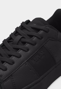 Μαύρο χαμηλό sneaker με υφασμένα δερμάτινα πάνελ, μαύρα κορδόνια που ταιριάζουν και το λογότυπο «Replay» ανάγλυφο στο πλάι κοντά στα οπές των κορδονιών.