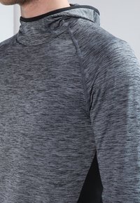 Grau melierte Kapuzen-Sweatjacke aus strukturiertem Material, mit taillierter Passform und kontrastierenden schwarzen Akzenten an den Seiten und am Kragen.