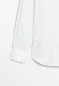 Weißes Langarmhemd mit glatter Textur, ausgestattet mit eng anliegenden Manschetten und einem leicht geschwungenen Saum, aus leichtem Stoff gefertigt.