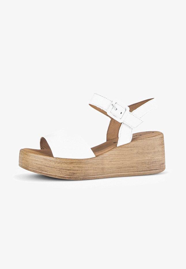 White leather platform sandals with a wide front strap and adjustable ankle strap. Wooden textured wedge heel, approximately two inches high.