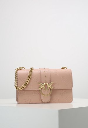 Borsa a mano in pelle rosa chiaro con motivi di uccelli impressi a rilievo, chiusura doppia a forma di uccello dorata e tracolla a catena spessa dorata su una superficie bianca.