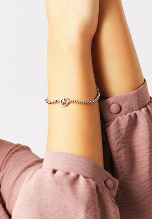 Silberne Perlenarmband mit einem runden Friedenssymbol-Anhänger. Das Band ist flexibel und hat eine glatte, glänzende Oberfläche.