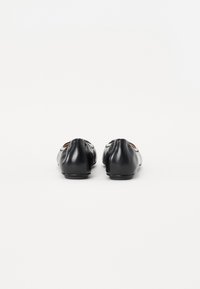 Ballerines noires en cuir avec un bout arrondi, texture lisse et design minimaliste. Les détails incluent des coutures discrètes et une semelle plate.