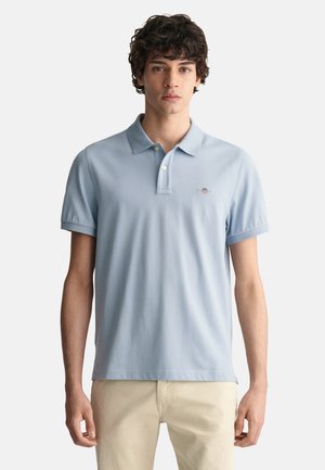 Polo de color azul claro en suave algodón con cuello, tapeta de dos botones y mangas cortas. Pequeño logo bordado en el pecho.
