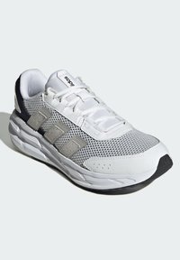 White athletic shoe with mesh upper, gray accents, padded collar, and textured sole. Features three gray stripes on the side.