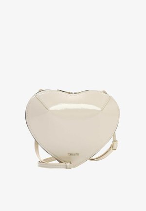 Crèmekleurige, hartvormige crossbodytas met een glanzende afwerking, ritssluiting en verstelbare band tegen een witte achtergrond.