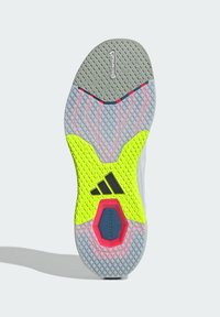 Η εξωτερική σόλα παπουτσιού Adidas διαθέτει γκρι λαστιχένια επιφάνεια με κίτρινη λεπτομέρεια και κόκκινο εξαγωνικό στοιχείο. Περιλαμβάνει υφή για καλύτερη πρόσφυση.