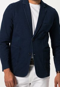 Marineblauwe blazer van gestructureerde stof, met een getailleerde pasvorm, twee voorzakken, een enkele knoopsluiting en een lichte voering.