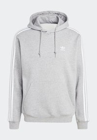 Grå sweatshirt med huva, vita dragsnören, framficka i kengurustil och tre vita ränder längs varje ärm. Har en liten vit logotyp.