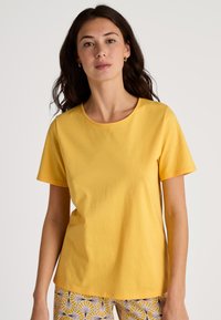 Geel katoenen t-shirt met een ronde halslijn en korte mouwen. Heeft een gladde textuur en een ontspannen pasvorm. Achtergrond is plain wit.