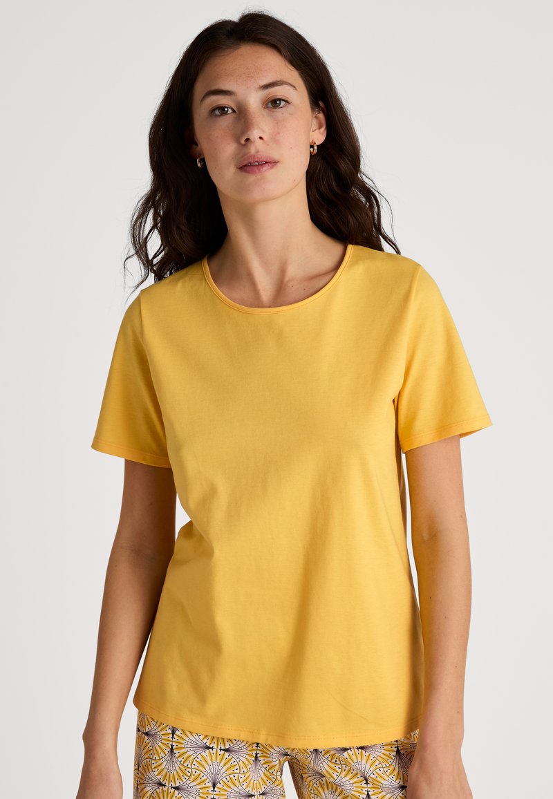 Geel katoenen t-shirt met een ronde halslijn en korte mouwen. Heeft een gladde textuur en een ontspannen pasvorm. Achtergrond is plain wit.