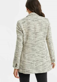 Texturerad blazer i gräddfärg med svarta fläckar, enknäppt design, slagkrage och knappade manschetter. Bakdelen har en centralseam.