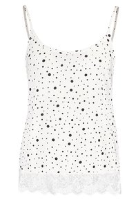 Top sin mangas blanco con lunares negros, con encaje en la parte inferior y tirantes delgados. Tela suave con un corte relajado.