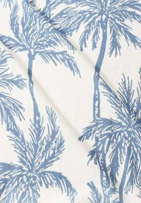 Tissu en coton avec un motif de palmier bleu sur fond blanc, présentant des textures de branches et de feuilles détaillées. Fini lisse.