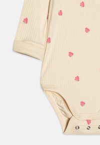 Beige ribbet bodysuit med små lyserøde og grønne blomster mønstre, med trykknapper i bunden og foldede ærmer.