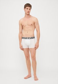 White boxer briefs with a black elastic waistband featuring the text "SQUARE" prominently displayed. Smooth, fitted design.