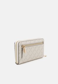Beige Leder-Wallet mit einem Reißverschluss, geprägtem Logo-Muster, goldenen Beschlägen und einem kontrastierenden schwarzen Rand entlang der Kanten.