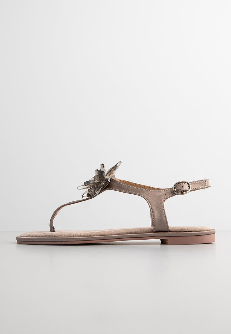 Hellbraune Sandale mit floralem Akzent, flacher Sohle, verstellbarem Knöchelriemen und einer strukturierten Innensohle für Komfort.