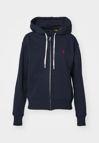 Marinblå zip-up hoodie i bomullsblandning, med en ficka fram, vita snoddar och en liten röd logotyp på vänster bröst.