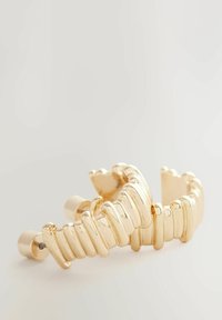 Goldfarbener Metallhaarnadel mit einem wellenförmigen Design, das abwechselnd glatte und strukturierte Segmente aufweist. Abgerundete Enden und ein sicherer Verschluss.