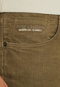 Pantaloni in corduroy verde oliva con superficie testurizzata, caratterizzati da logo ricamato "PME LEGEND AMERICAN CLASSIC" e dettaglio del bottone nero.