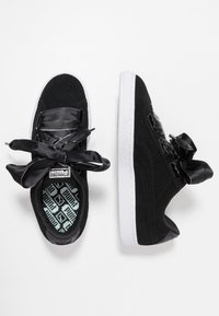 Černé semišové tenisky se širokými černými saténovými šňůrkami, bílou strukturovanou gumovou podrážkou a vzorovanou černou a tyrkysovou stélkou.