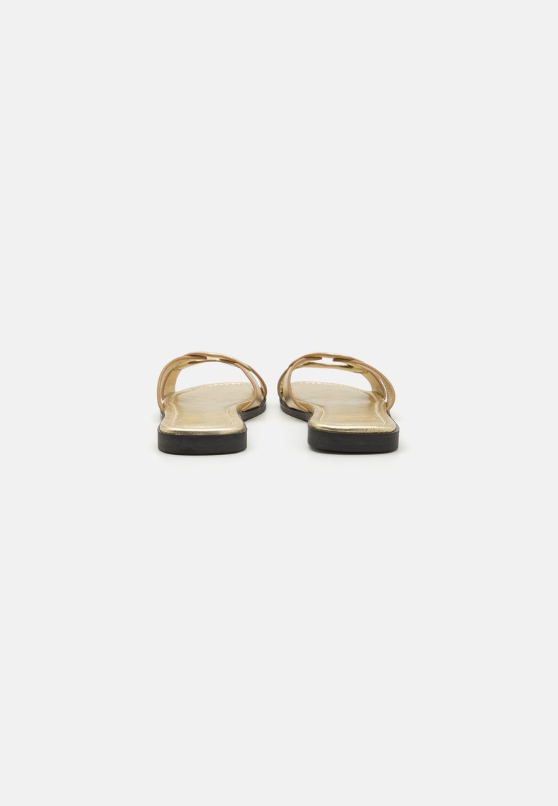 Flache Sandalen mit einem goldenen, metallischen Obermaterial und zwei dünnen Riemen. Beigefarbenes Fußbett und schwarze Gummisohle. Einfaches und minimalistisches Design.