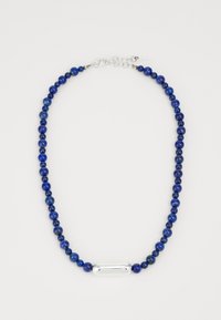 Κολιέ από μπλε λαπις λαζουλί με ασημένιο οβάλ στοιχείο, διαθέτει κλείσιμο τύπου μπάλα και αλυσίδα. Οι χάντρες διαφέρουν σε μέγεθος, δημιουργώντας μια υφητική εμφάνιση.