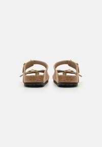 Sandales en cuir suédé marron avec des sangles réglables, boucles dorées, semelle en liège et semelle en caoutchouc noire. Design ouvert à l'arrière pour un enfilage facile.