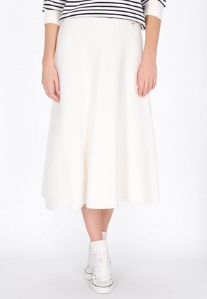 Maxi rok in het wit, gemaakt van gestructureerde stof. Heeft een elastische tailleband en een uitlopende stijl, gecombineerd met witte high-top sneakers.
