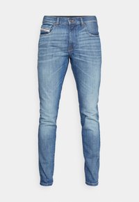 Light blue denim jeans with a slim fit, featuring five pockets, contrasting stitching, and a classic zip fly with a button closure.