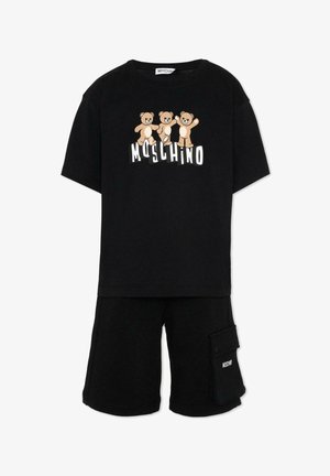 Maglietta nera a maniche corte con tre orsacchiotti sopra la scritta bianca "MOSCHINO", abbinata a pantaloncini neri con una tasca laterale e logo.