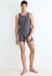 Canotta grigia in cotone e pantaloni corti fitted abbinati con una texture liscia. La canotta presenta un classico scollo a girocollo e spalline larghe.