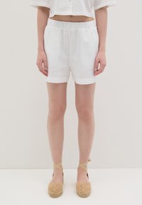 Witte linnen shorts met een elastische tailleband, met een soepele textuur en omgerolde zoom, gecombineerd met geweven tan espadrilles.