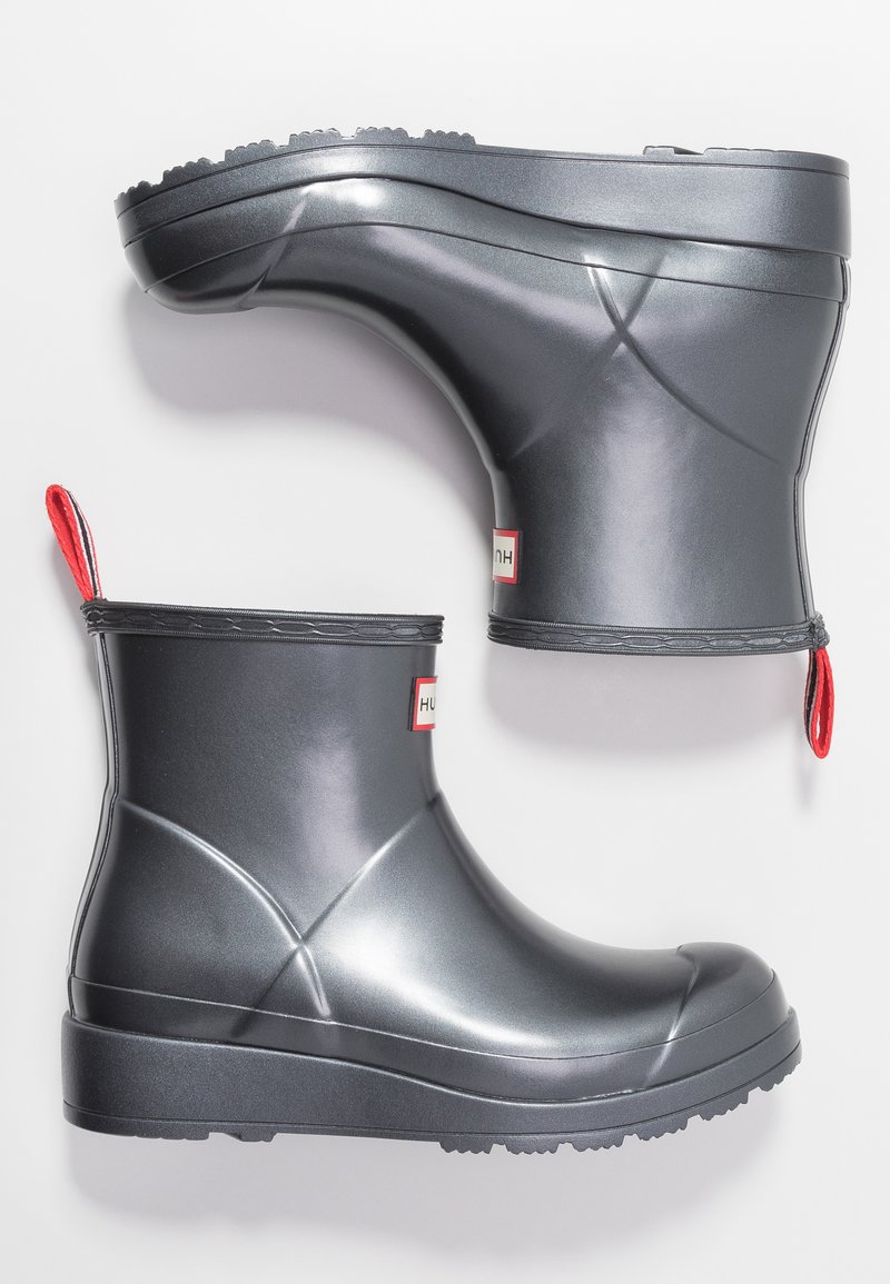 Botas de tobillo de goma grises con un acabado brillante, tirador rojo y una suela texturizada. Logo de marca identificable en el lateral.