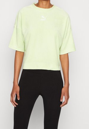 Top de forro polar corto de manga corta en verde claro, con cuello redondeado y un sutil logo blanco de Puma. Combinado con leggings negros.