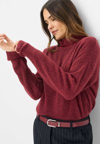 Bordeaux gebreide trui met lange mouwen, geribbelde manchetten en een zachte textuur, gecombineerd met een bijpassende riem over gestreepte broek.