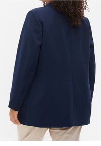 Marinblå kavaj med en strukturerad design, långa ärmar och en enkel slits. Tillverkad av ett slätt tyg, med en skräddarsydd silhuett och minimalistisk stil.