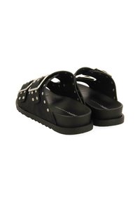 Des sandales à glissière en caoutchouc noir sont dotées de sangles réglables avec des boucles en métal argenté et des accents cloutés, conçues avec une semelle intérieure texturée pour le confort.