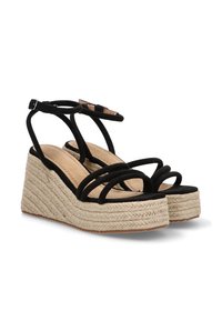 Sandalias de cuña de ante negro con múltiples tiras finas y una plataforma de yute tejido. La altura del tacón es moderada y cuenta con una suela texturizada.
