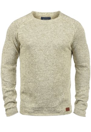 Pull beige à manches longues en maille avec col rond, tissu texturé et petit patch en cuir près de l'ourlet sur le côté gauche avant.