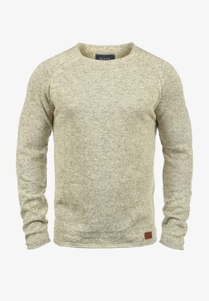 Beiger, langärmliger Strickpullover mit Rundhalsausschnitt, strukturierter Stoff und kleinem Lederpatch vorne am linken Saum.