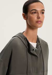 Grå hættetrøje med en afslappet pasform, der har en unik cowl-hals og en lynlåsdetalje, lavet af et glat og blødt stof.