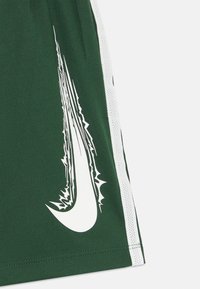 Gröna sportshorts med en vit Nike-logotyp med en taggig design, accentuerade av vita sidorstänger och tillverkade av textil med en strukturerad,ventilerande kvalitet.